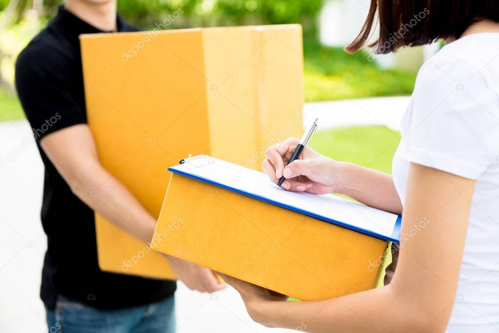 Woman signing document, receiving parcel box from delivery man