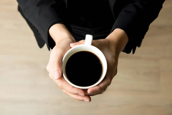 Manos de mujer sosteniendo la taza de café con café negro - vista superior —  Fotos de Stock