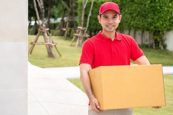 Pengiriman pria berseragam merah memegang kotak paket — Stok Foto