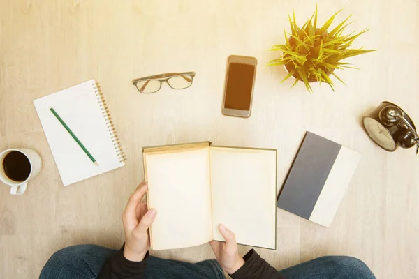 Young woman sitting on the floor opening book - top view — Stock Photo, Image