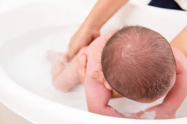 Мать купает новорожденного ребенка в ванной — стоковое фото