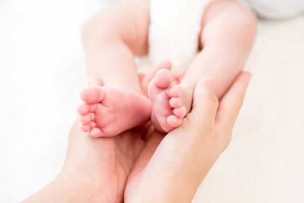Руки матери нежно держат маленькие детские ножки — стоковое фото