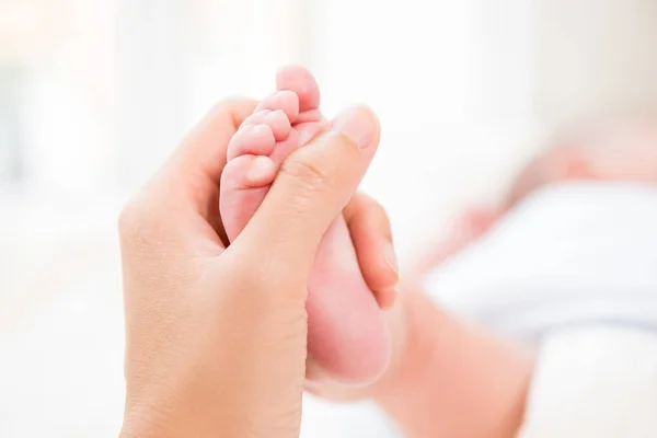 Рука матери нежно касается маленькой ножки ребенка — стоковое фото