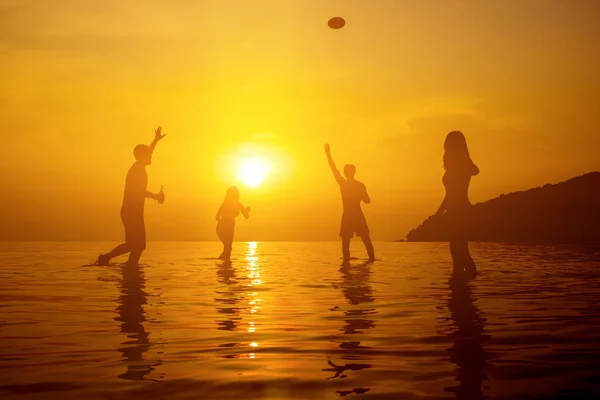 Σιλουέτα των ανθρώπων που παίζουν στην παραλία το καλοκαίρι ηλιοβασίλεμα — Φωτογραφία Αρχείου