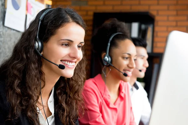 Mujer de negocios sonriente trabajando en el centro de llamadas con su multietnia — Foto de Stock