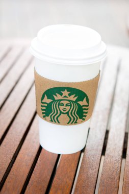 Bangkok, Tayland - 29 Haziran 2016: Starbucks, ahşap masa kolunda logo olan kahve fincanını kaldırdı