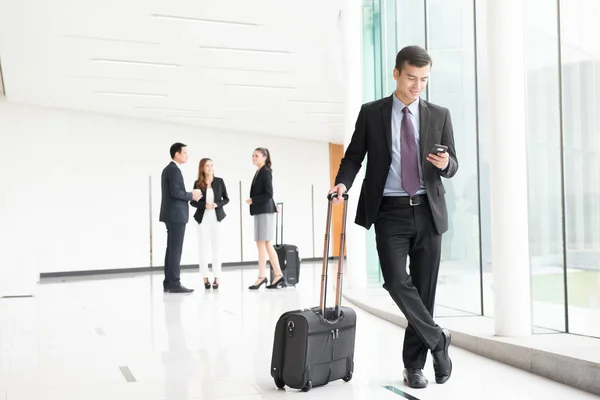Business people with luggage in building hallway — Stock Photo, Image
