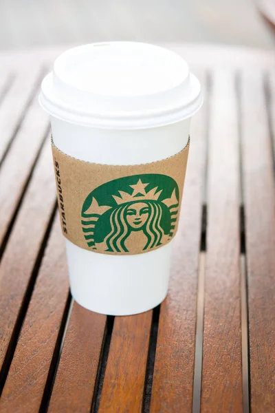 Starbucks take away coffee cup with brand logo on wood table — Stock Photo, Image