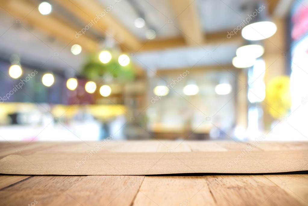 Brown paper on wood table top in blur restaurant interior backgr