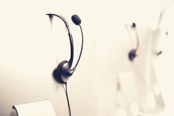 Microphone headsets hanging on computer monitors in call center — Stock Photo, Image