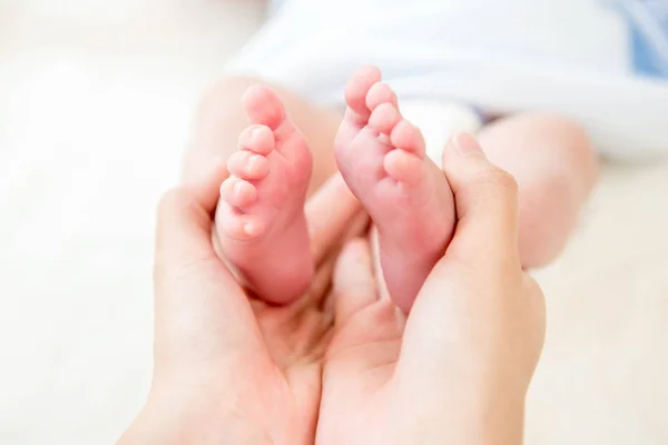 Руки матери нежно держат маленькие детские ножки — стоковое фото