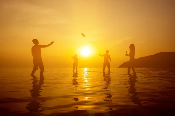 Silhouet van mensen spelen op het strand in de zonsondergang — Stockfoto