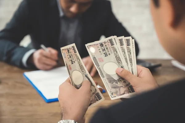 Empresário contando dinheiro, ienes japoneses contas, enquanto fazendo agr — Fotografia de Stock