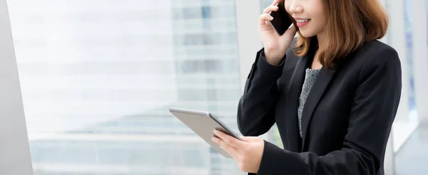 Geschäftsfrau telefoniert mit Smartphone, während sie Tablet-Computer anschaut — Stockfoto
