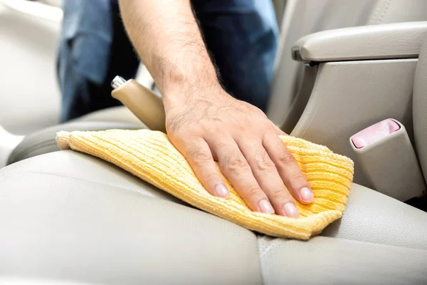 Un hombre limpiando asiento de coche de cuero con tela de microfibra — Foto de Stock