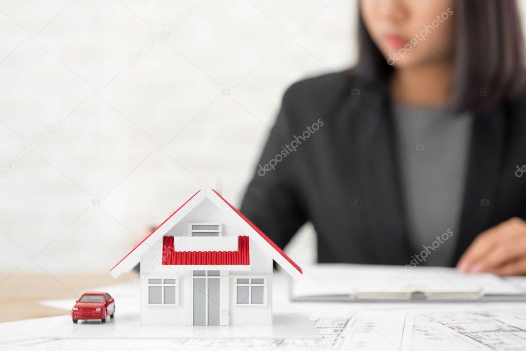 House model on blueprint paper at the table with blurred busines