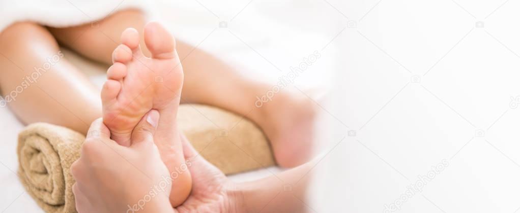 Professional therapist giving traditional thai foot massage to a