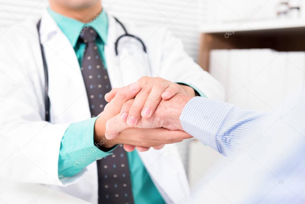 Doctor holding senior male patient hand 