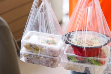 Paket poşetlerde Asyalı yemek kutuları teslimatçı adam tarafından eve getirildi.