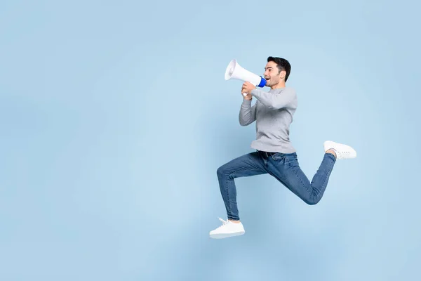 Jonge Actieve Man Springen Schreeuwen Megafoon Geïsoleerd Lichtblauwe Achtergrond Met — Stockfoto