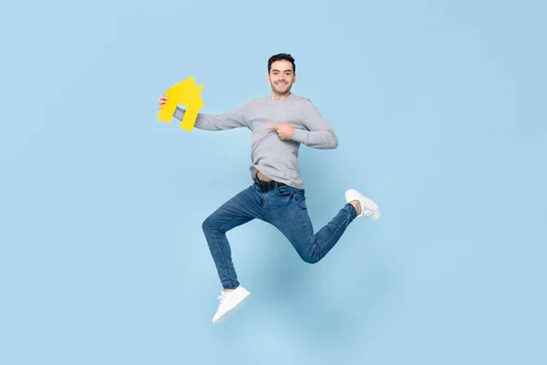 Счастливый Красавец Прыгает Указывает Желтую Модель Дома Изолированную Синем Студийном — стоковое фото