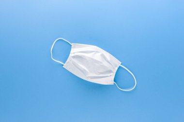 Açık mavi kağıt arkaplan görünümünde yeni temiz beyaz tıbbi yüz maskesi izole edildi