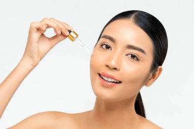 Güzel bir Asyalı kadın güzellik ve cilt bakımı kavramları için yüzüne yaşlanma önleyici serum sürüyor.