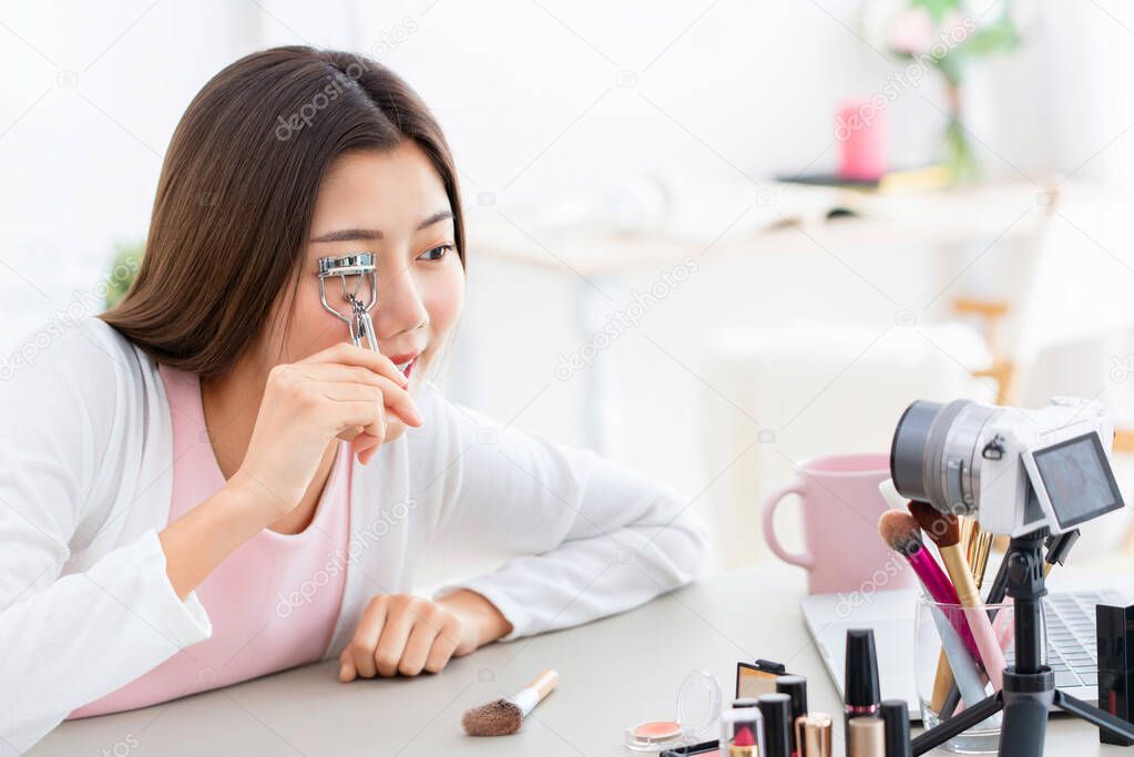 Young Asian girl beauty influencer record video while using eyelash curler at home