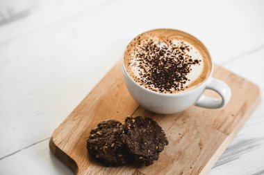 Kahve fincanında sıcak latte kahve ve çikolatalı kurabiyeler. Kahvaltı için kafeteryada.
