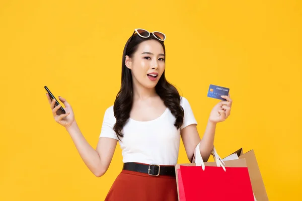 Piękna Uśmiechnięta Azjatka Torbami Zakupy Smartfonem Kartą Kredytową Dłoni Odizolowana — Zdjęcie stockowe
