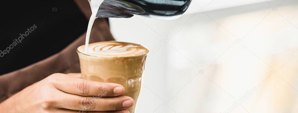 Banner of professional barista pouring steamed milk into coffee glass cup making beautiful latte art Rosetta pattern