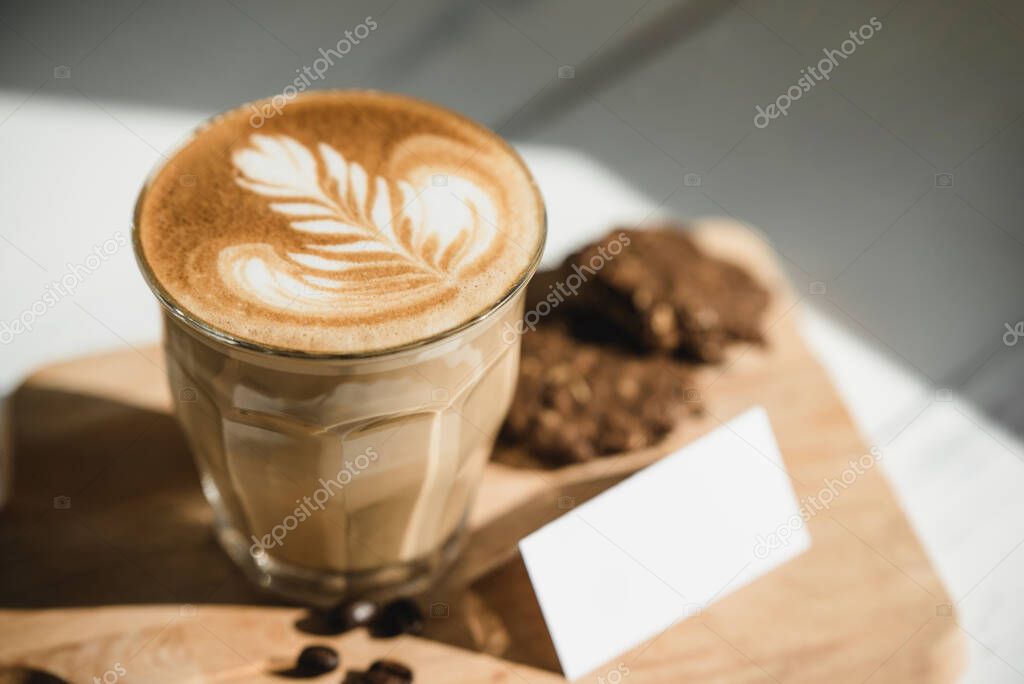 Fresh brewed Cappuccino coffee with beautiful latte art on wooden platter ready to drink