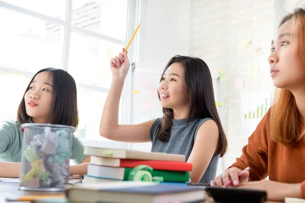 アジア系女子大生が教室で質問をしながら手を挙げて勉強 — ストック写真