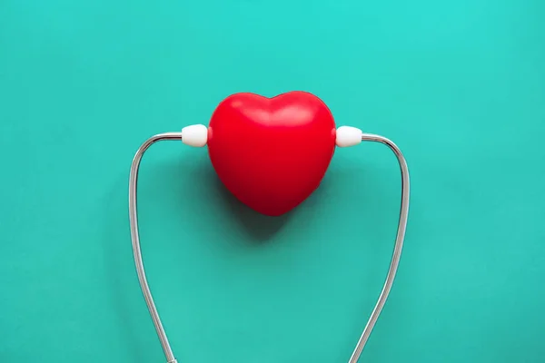 Roter Herzförmiger Ball Mit Stethoskop Auf Grünem Hintergrund Gesundheitswesen Und — Stockfoto