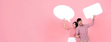 Happy smiling young Asian couple with speech bubbles studio shot on pink banner background with copy space clipart