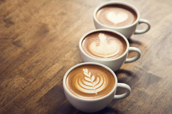 Tuoreita Kahveja Kaunis Latte Taidetta Pinnalla Kolme Kuppia Peräkkäin Puinen — kuvapankkivalokuva