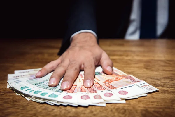 闇のオフィスで彼の机の上にお金を与えるビジネスマン ロシアのルーブル紙幣 贈収賄と汚職の概念 — ストック写真