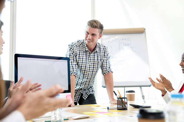Successful casual businessman being congratulated by his colleagues in a board room meeting