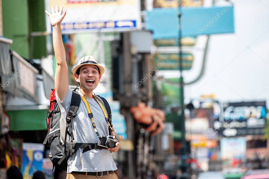 Excited Asian tourist man raising hand up for greeting someone in Khaosan road Bangkok Thailand