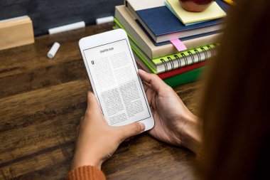 Masada taşınabilir dijital tabletten elektronik kitap okuyan öğrenci