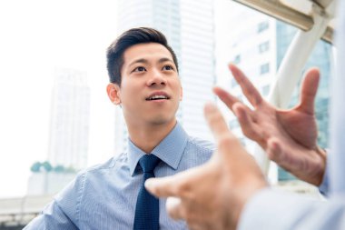 Yakışıklı Asyalı Çinli iş adamı şehirde ortağıyla konuşuyor.