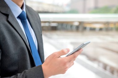 İnternet 'te online bilgi aramak için akıllı telefon sörfü yapan bir işadamı