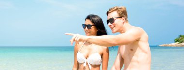 Genç ırklar arası turist çiftler sahilde yürürken yaz tatillerinde Koh Samui Tayland 'da güzel vakit geçiriyorlar. Panoramik pankart.