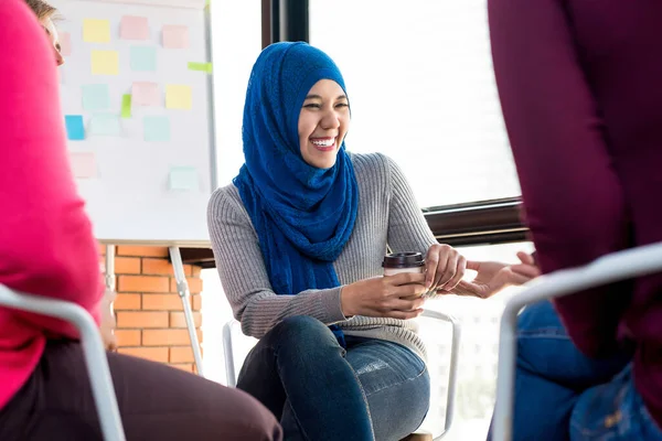 若いイスラム教徒の女性はグループミーティングで彼女の友人と楽しく話して笑っています — ストック写真
