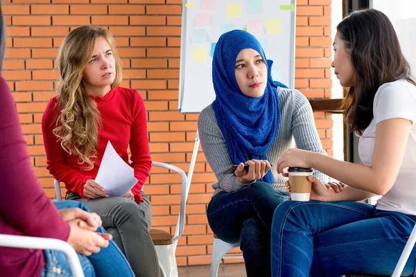 Diverse women sharing problems and support eacher in group meeting therapy