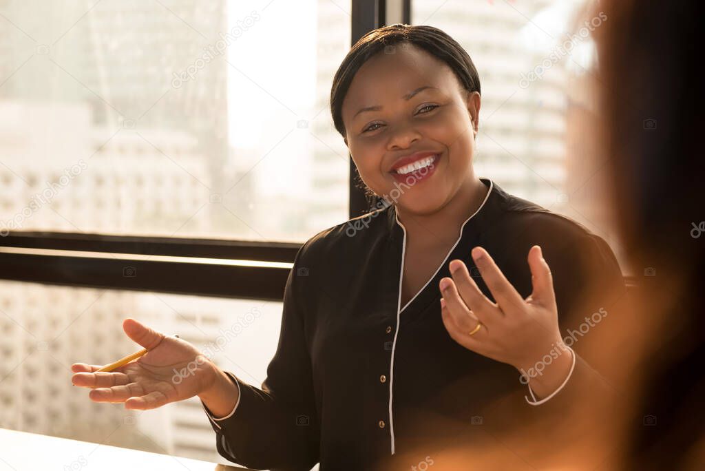 Friendly black businesswoman leader discussing work with colleague at the meeting in office