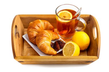 Cam bardakta limonlu çay, kruvasan ve ahşap tepside hurma. Beyaz arkaplanda izole et
