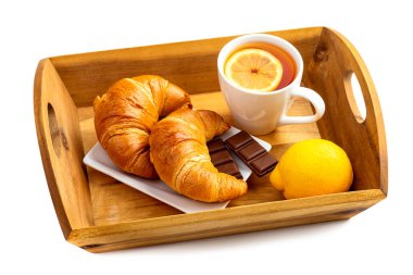 Cam bardakta limonlu çay, kruvasan ve ahşap tepside hurma. Beyaz arkaplanda izole et