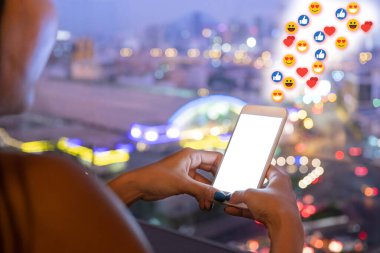 Sosyal medyada paylaşmak için gece emojili telefon kullanan bir kadın. Bulanık bulut