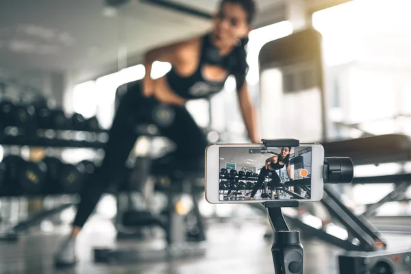 Mujer usando un teléfono para vlogging o foto selfie. Asiática mujer haciendo ejercicio con dumbbell — Foto de Stock